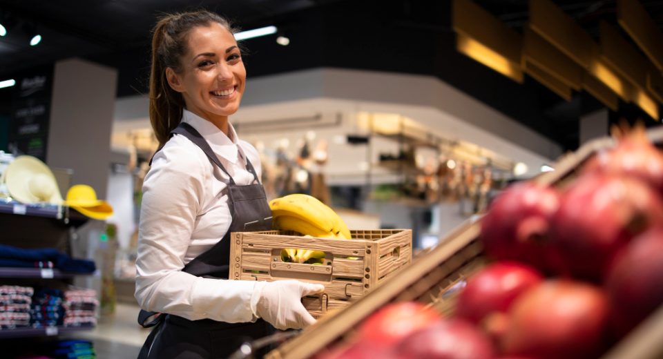 supermarket worker supplying fruit department with food